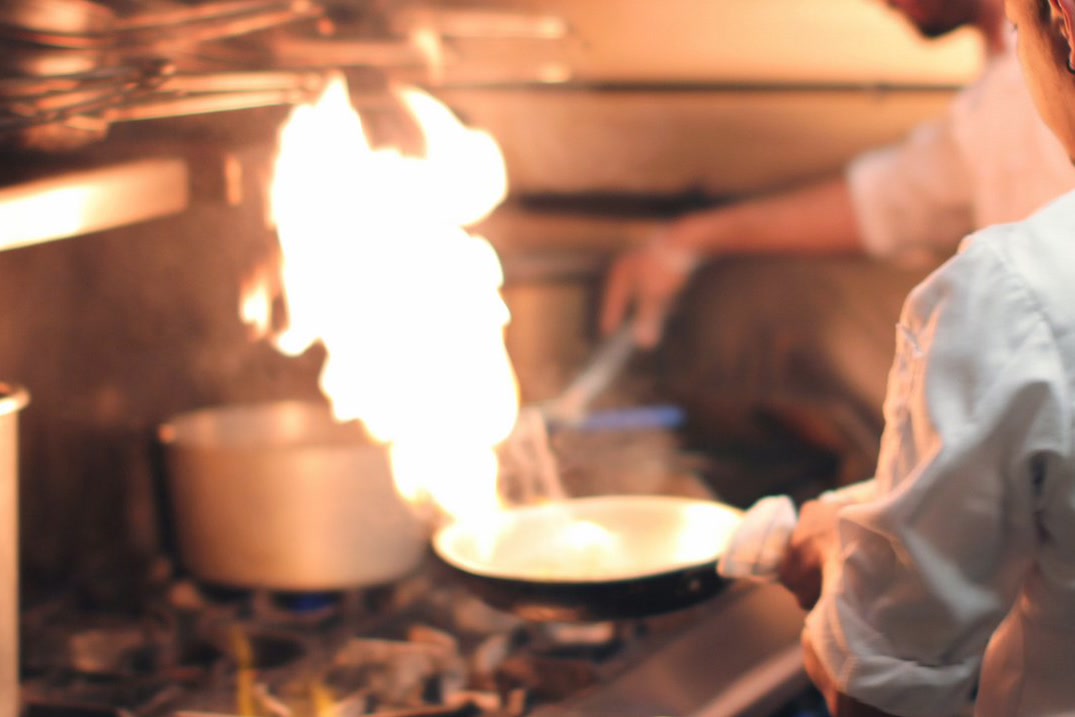 Cocinero de Mr. Lasaña flameando un salteado en la cocina del restaurante